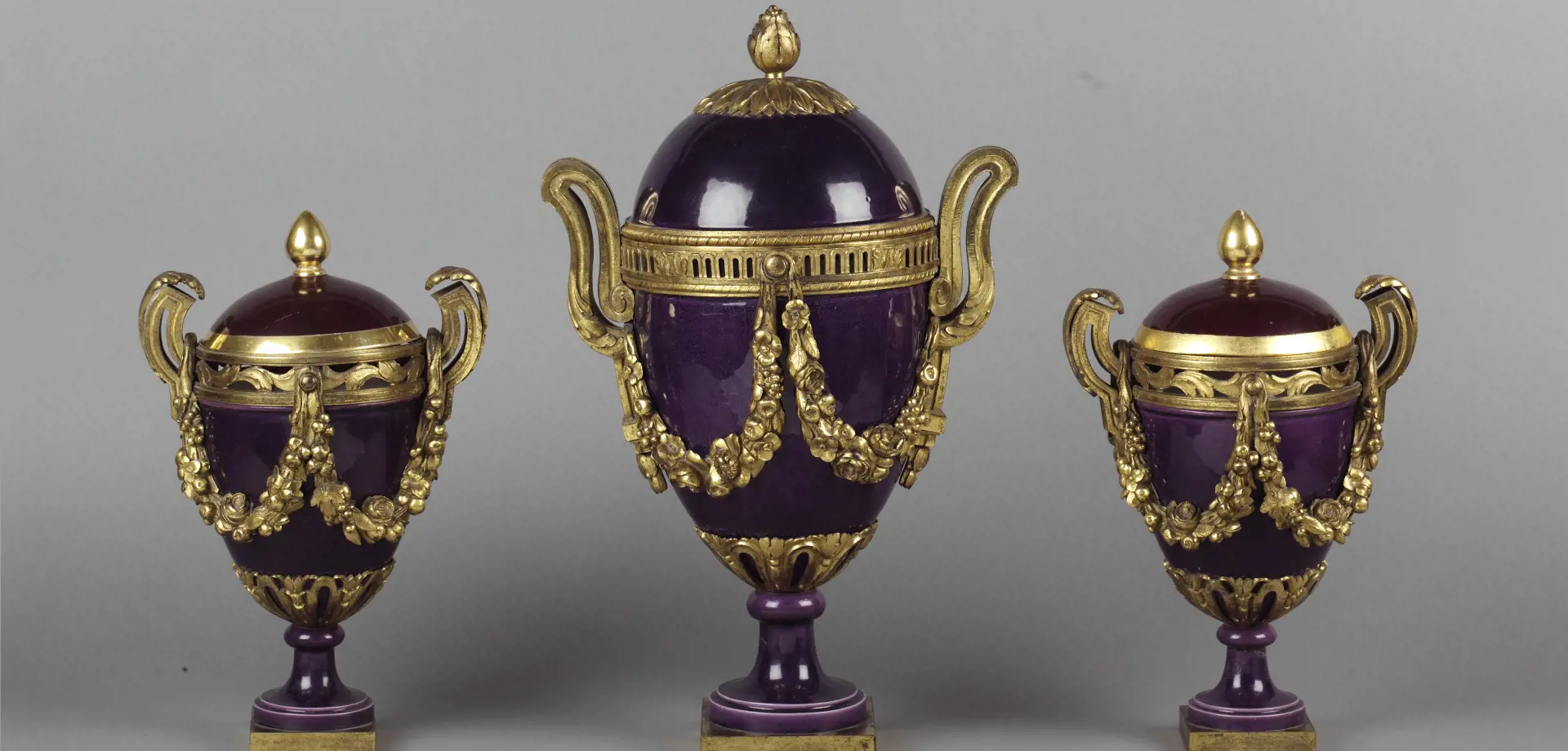 A Louis XVI gilt-bronze mounted Sèvres violet glaze porcelain garniture of three vases, two with covers